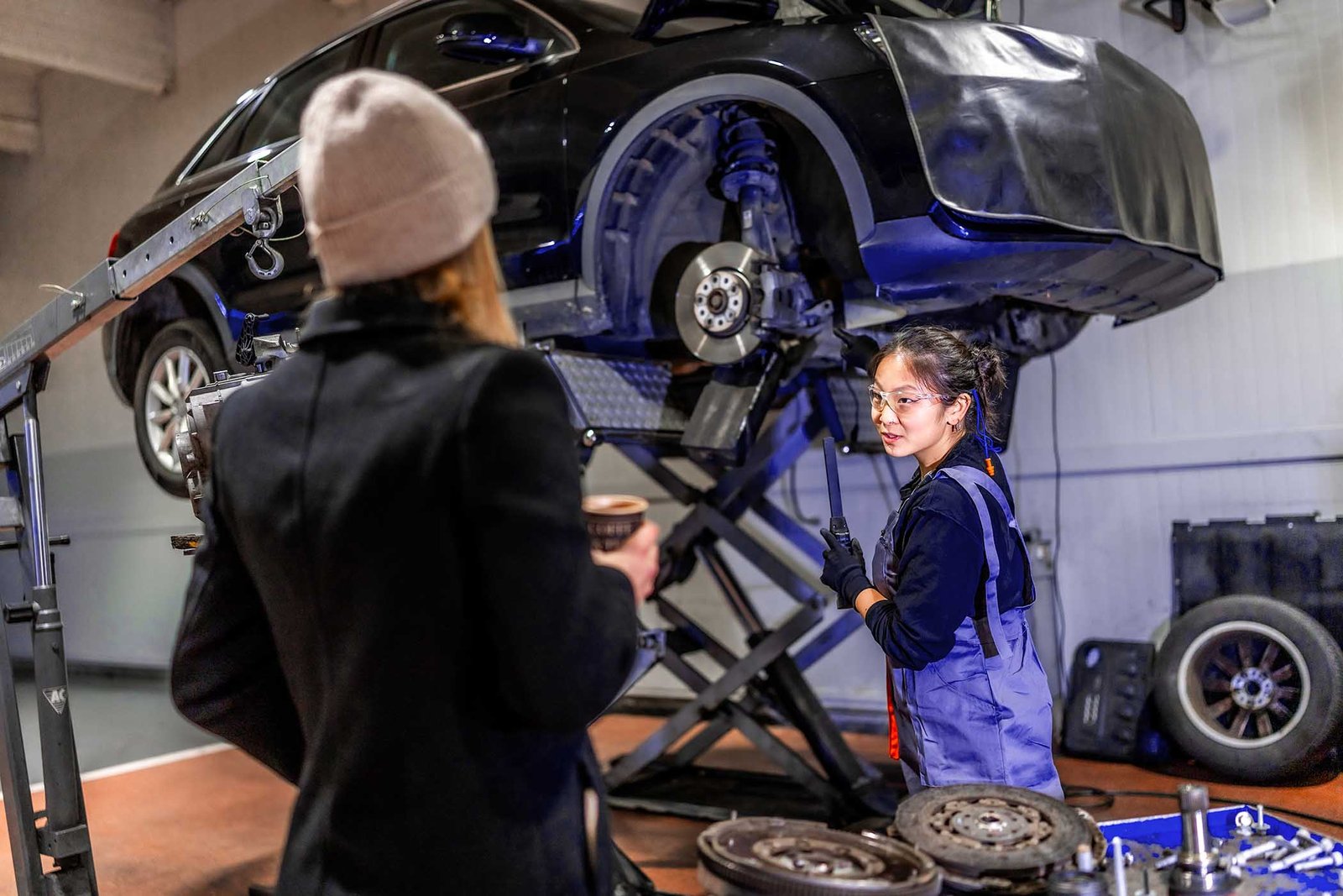 female-mechanic-showing-repaired-car-to-customer-i-JJYWPES.jpg